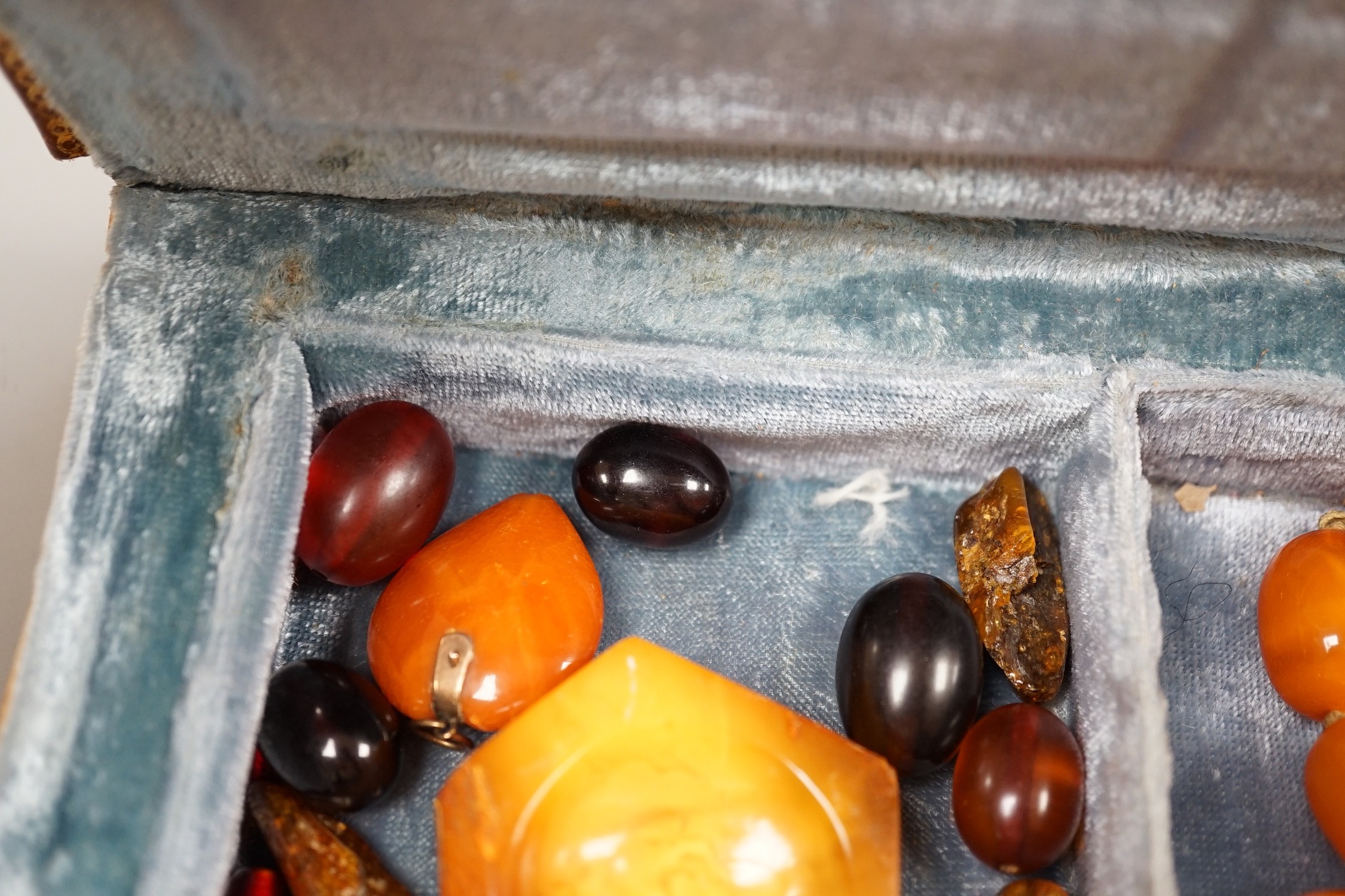 A single strand amber bead necklace, 48cm, gross 52 grams, together with other loose amber and amberoid beads and an amber pendant in a simulated book box.